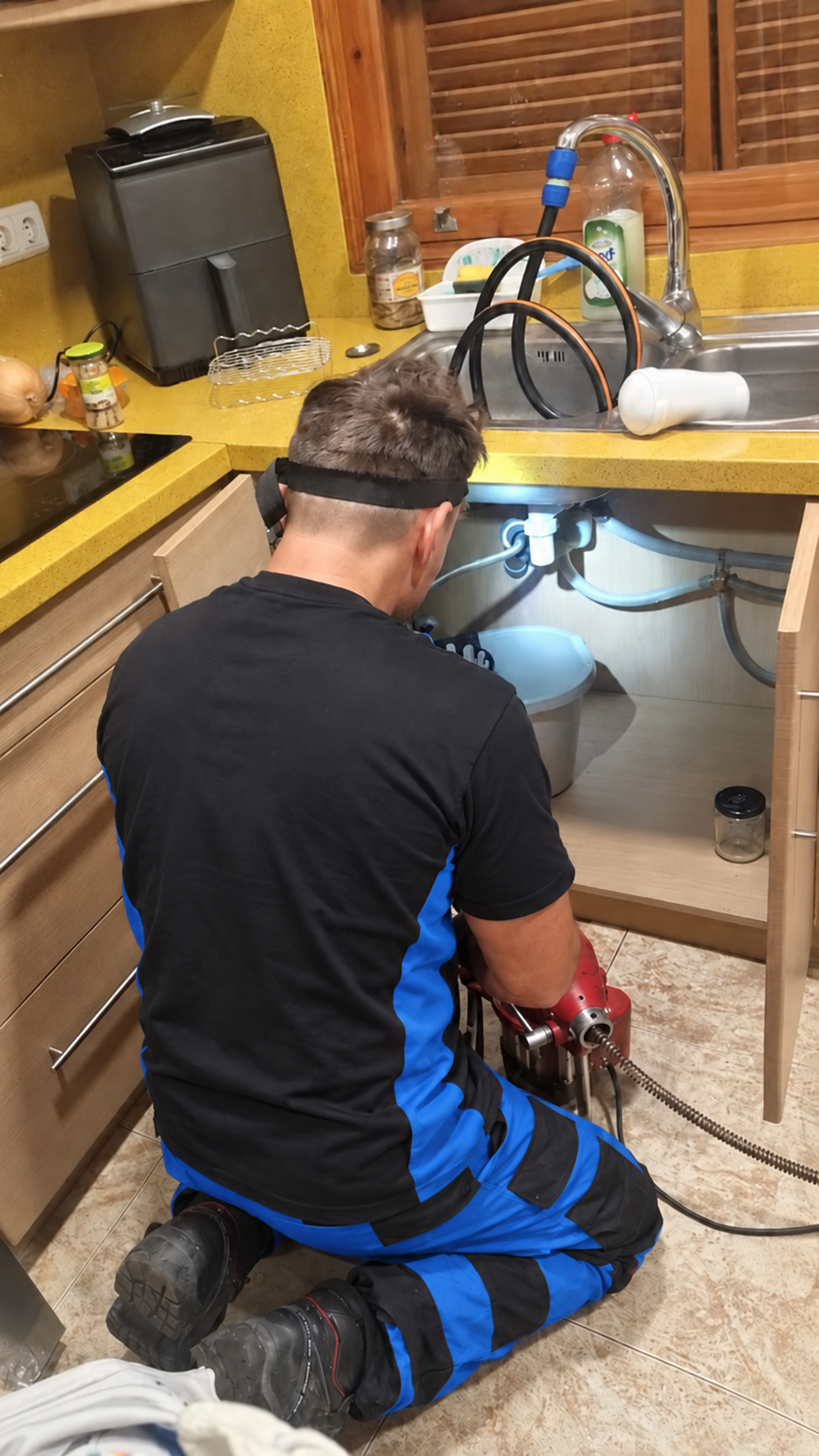 Técnico trabajando en el desagüe bajo un fregadero